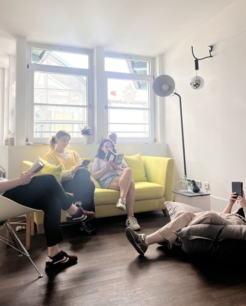 Personen sitzen auf Couch und Boden und lesen